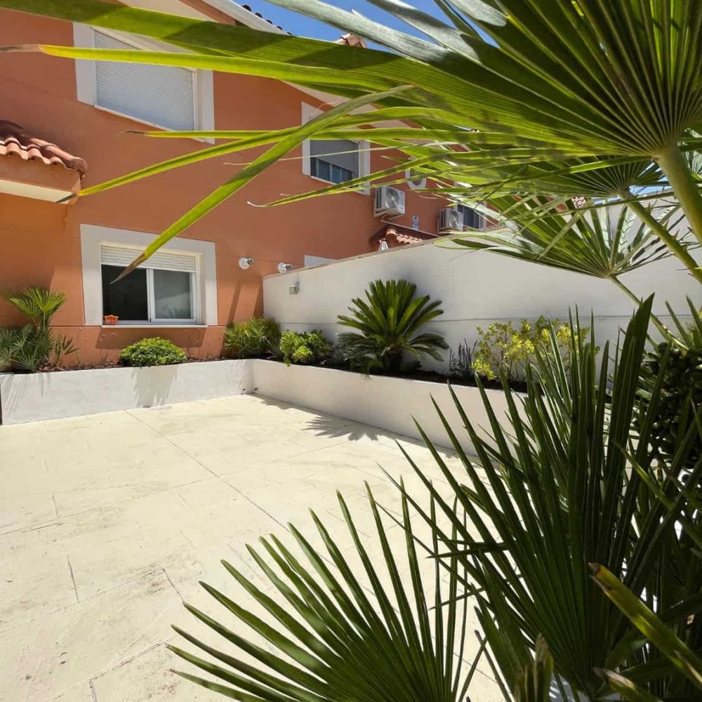 Jardín con plantas tropicales y zona de descanso en vivienda en España.